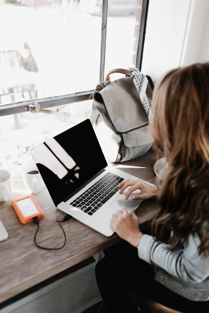 A young woman works at a café, using her laptop