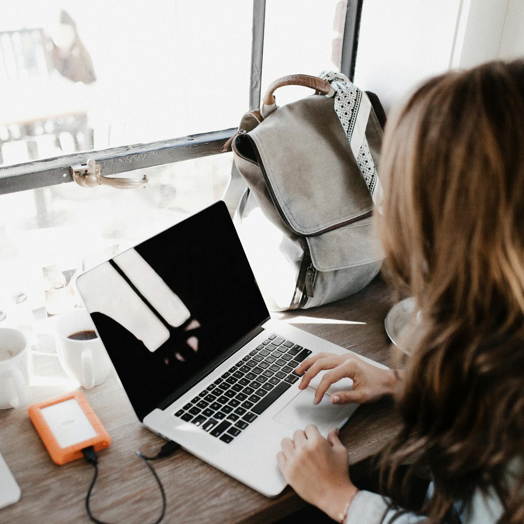 A young woman works at a café, using her laptop