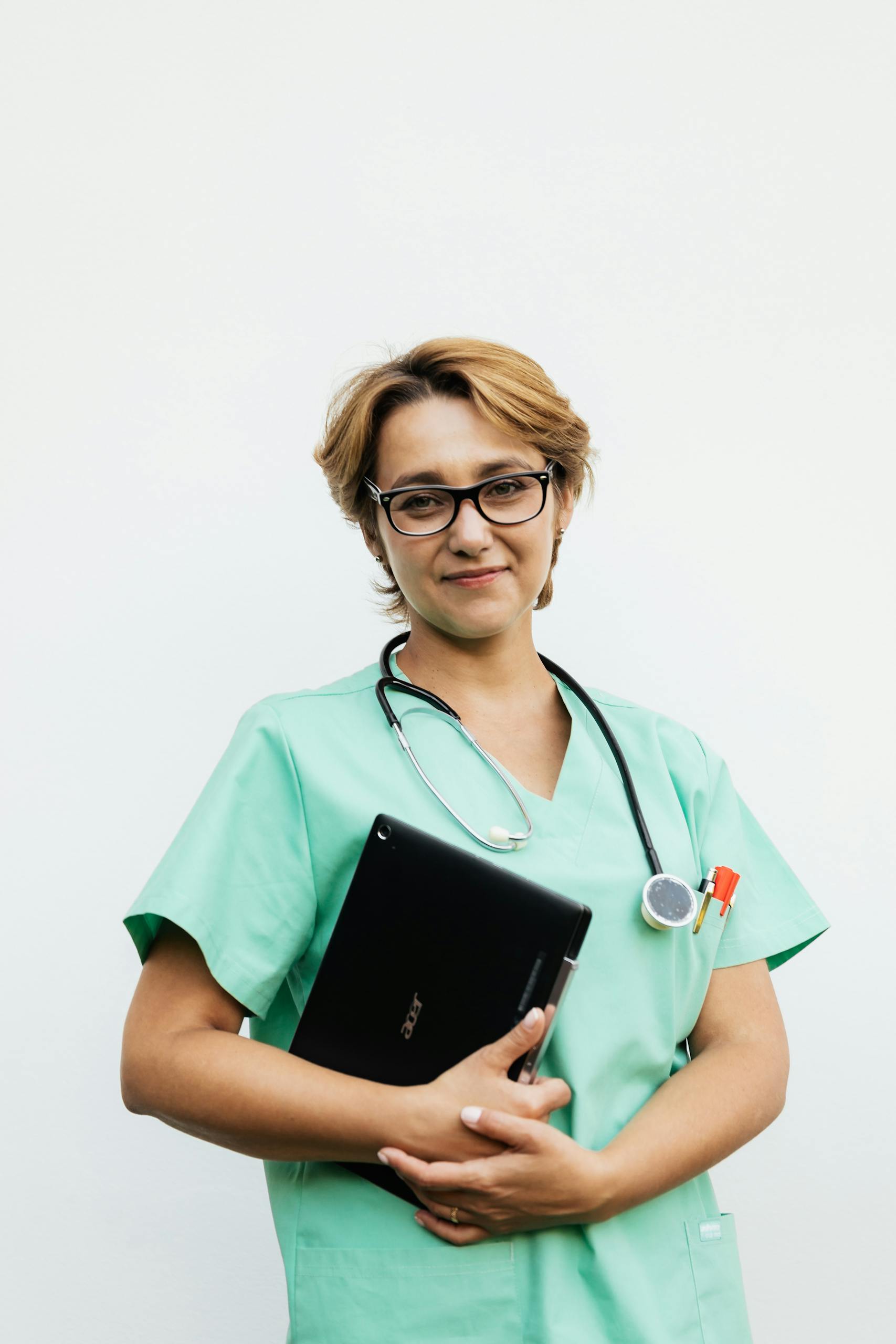 Confident female nurse with eyeglasses holding a tablet and stethoscope.